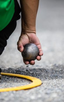 Hand holding petanque ball or boule. Man in yellow circle positi Hand holding petanque ball or boule. Man in yellow circle position area